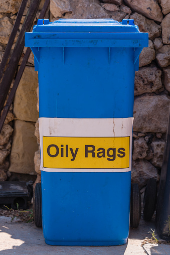 Blue bin with a sign on it for oily rags.