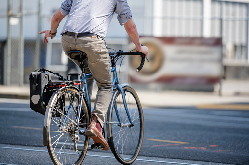 Ciclista monta en bicicleta a lo largo de la calle de la ciudad y se muestra con su maniobra de mano girando en una intersección photo