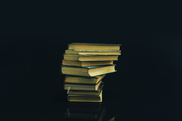 istock Old books on a glass table black background. 1160848001