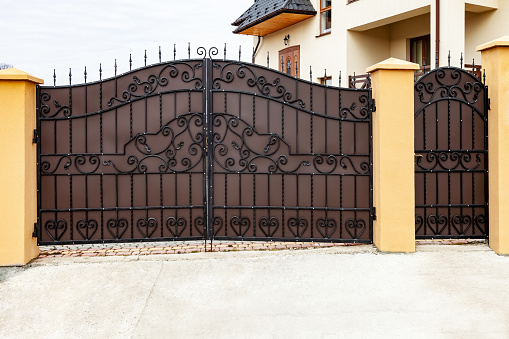 New forged metal double gates for entry of cars into the yard and wicket
