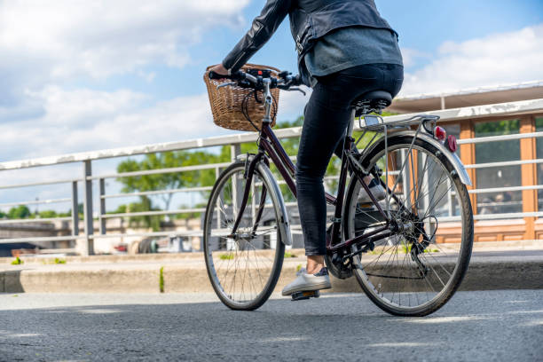 la femme monte le vélo avec le panier le long des rives de la seine - location vélo photos et images de collection
