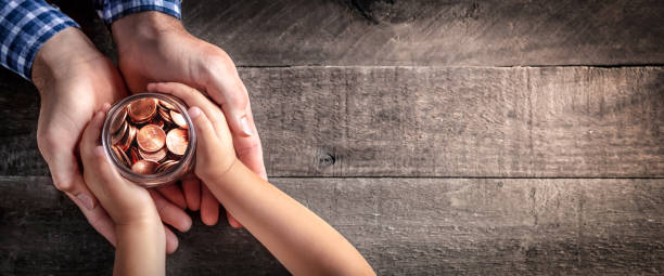 Father Giving Jar Of Coins To Child Hands Of Father Giving Jar Of Coins To Child On Wooden Table Background - Inheritance / Parent Providing For Children Concept kid holding fathers hand stock pictures, royalty-free photos & images