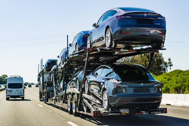 Car transporter carries Tesla Model 3 new vehicles July 4, 2019 Redwood City / CA / USA - Car transporter carries Tesla Model 3 new vehicles along the highway in San Francisco bay area, back view of the trailer; redwood city stock pictures, royalty-free photos & images