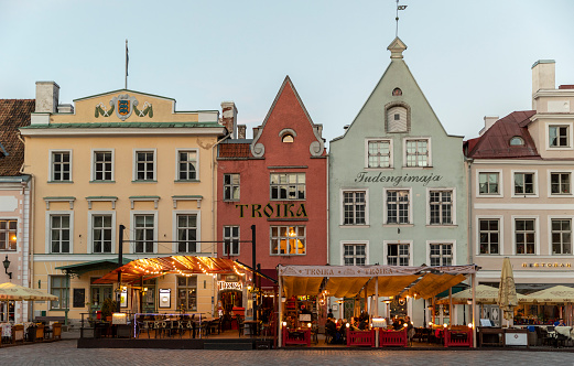 Tallinn, Estonia - May 15, 2019: Evening view of sidewalk cafes and diners on historic Town Square in the Old Town