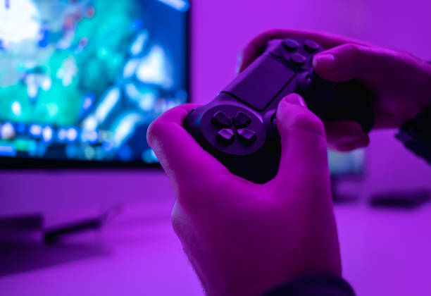 Crop hands with controller Closeup hands of anonymous male holding modern controller while playing video game in dark room gamepad photos stock pictures, royalty-free photos & images