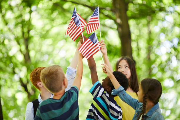istock Children raising us stick flags together 1160883588