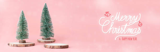 buon natale e felice anno nuovo all'albero di natale su tronchi di legno a fette di legno con confezione regalo su sfondo da studio rosa pastello. biglietto d'auguri per le festività natalizie.copia spazio per aggiungere testo. - backdrop design decoration winter foto e immagini stock