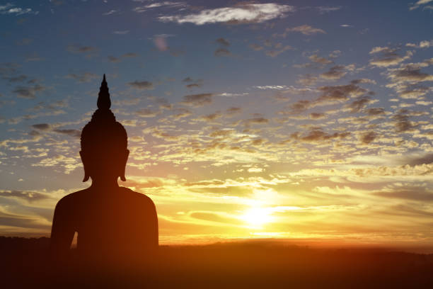 istock Silhouette statue of Buddha at sunset background 1160894316