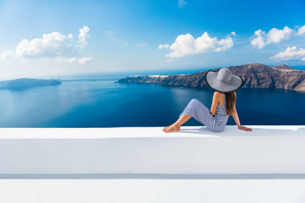 Europe Greece Santorini travel vacation - woman Europe Greece Santorini travel vacation. Woman looking at view on famous travel destination. Elegant young lady living fancy jetset lifestyle wearing dress on holidays. Amazing view of sea and Caldera greek culture photos stock pictures, royalty-free photos & images