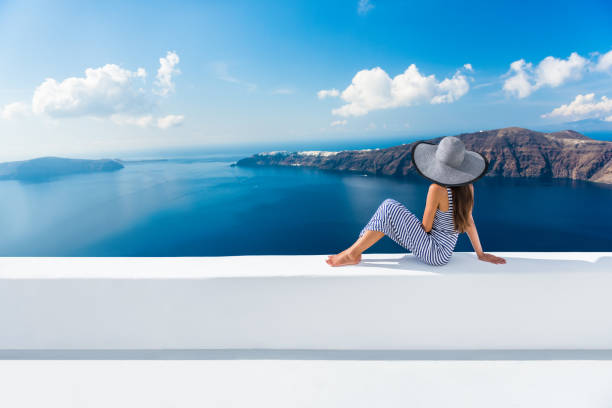 Europe Greece Santorini travel vacation - woman Europe Greece Santorini travel vacation. Woman looking at view on famous travel destination. Elegant young lady living fancy jetset lifestyle wearing dress on holidays. Amazing view of sea and Caldera elite stock pictures, royalty-free photos & images