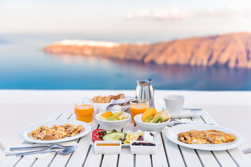 Breakfast table romantic by the sea. Perfect luxury breakfast table for two outdoors. Amazing caldera view on Santorini, Greece, Europe.