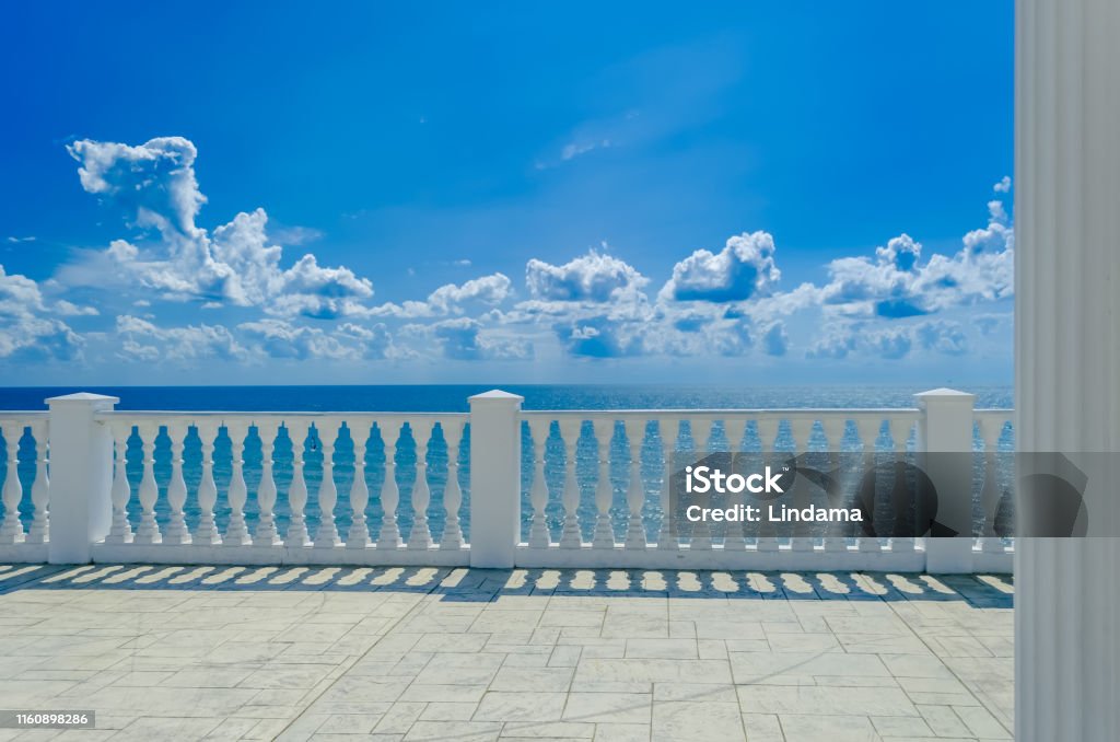 Terrace with white balusters to amazing views of the sea, sky and white clouds. Terrace with white balusters to amazing views of the sea, sky and white clouds. Summer Tropical Background. Balcony Stock Photo
