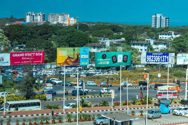 concurrido cruce, durante el tráfico de la hora pico, cerca del aeropuerto internacional de goa de dabolim. el espacio circundante se utiliza comercialmente y está cubierto con acaparamientos de anuncios - social media marketing branding sign fotografías e imágenes de stock