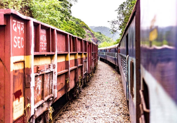 インド鉄道のコンカンセクションでカーブ曲がりを走行しながら、西ガーツの緑の中で撮影された美しい写真。左に止まっているsecの貨物列車は旅客列車にパスを与えている - travelogue ストックフォトと画像