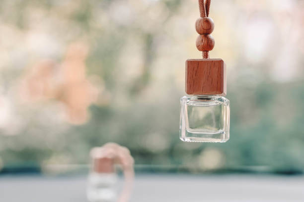 pequeña botella de vidrio con perfume de coche colgando en el coche. hermoso fondo borroso fuera de la ventana. - car freshner fotografías e imágenes de stock