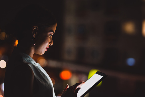 Shot of a young businesswoman using a digital tablet in an office at night
