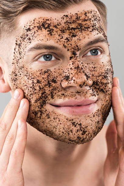 istock smiling young man applying scrub isolated on grey 1160924475