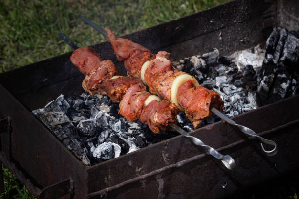 Grilled kebab cooking on metal skewer. Roasted meat cooked at barbecue. BBQ fresh beef meat chop slices. Traditional eastern dish, shish kebab. Grill on charcoal and flame, picnic, street food. kebab a la parrilla cocinando en brocheta de metal. carne asada cocinada en barbacoa. barbacoa rebanadas de chuleta de carne de res fresca. plato oriental tradicional, kebab shish. parrilla rallado al carbón y la llama, picnic, comida callejera