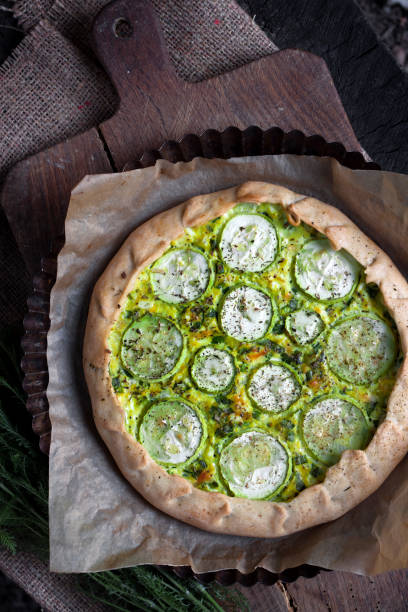 istock Homemade courgette and goat cheese pie on a dark rustic wooden board background 1160927433