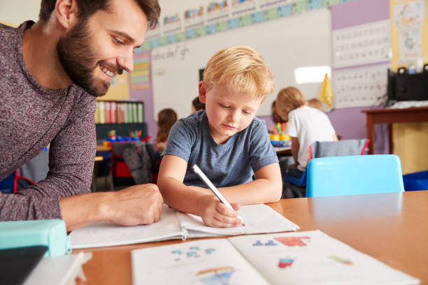 nauczyciel szkoły podstawowej dający męskiemu uczniowi wsparcie w klasie - elementary school education elementary student teacher zdjęcia i obrazy z banku zdjęć