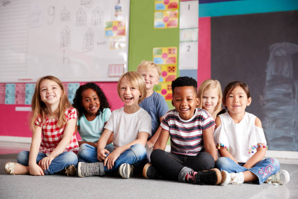 istock Portrait Of Elementary School Pupils Sitting On Floor In Classroom 1160927918