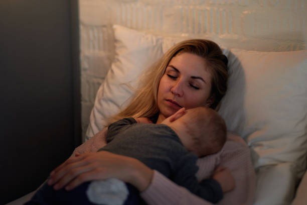 istock Tired mother naps while baby sleeps on her 1160927936