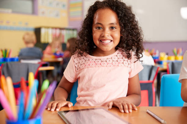 portrait of female pupil in elementary school drawing using digital tablet in classroom - school child education furniture imagens e fotografias de stock