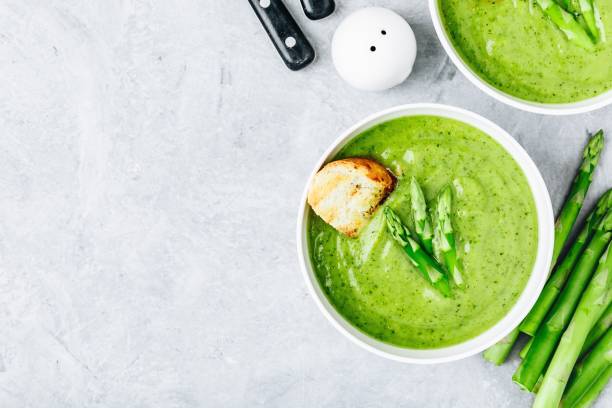 istock Asparagus cream soup with croutons on gray stone background. 1160928586