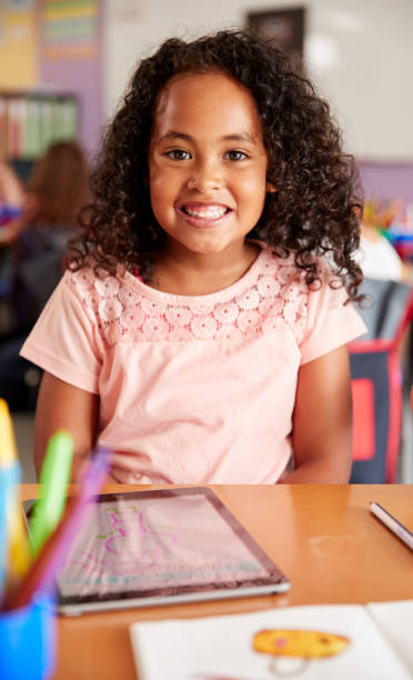 istock Portrait Of Female Pupil In Elementary School Drawing Using Digital Tablet In Classroom 1160928595