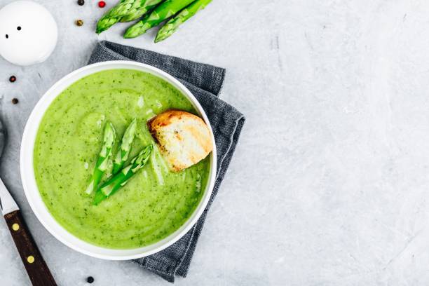istock Asparagus cream soup with croutons on gray stone background. 1160928609