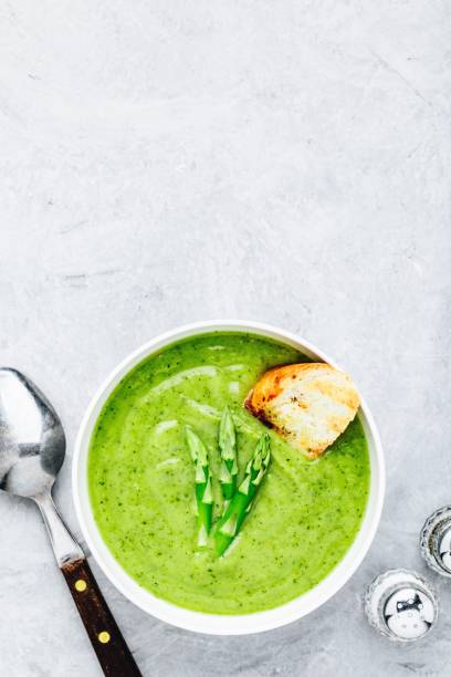 istock Asparagus cream soup with croutons on gray stone background. 1160928665