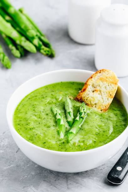 istock Asparagus cream soup with croutons on gray stone background. 1160928725