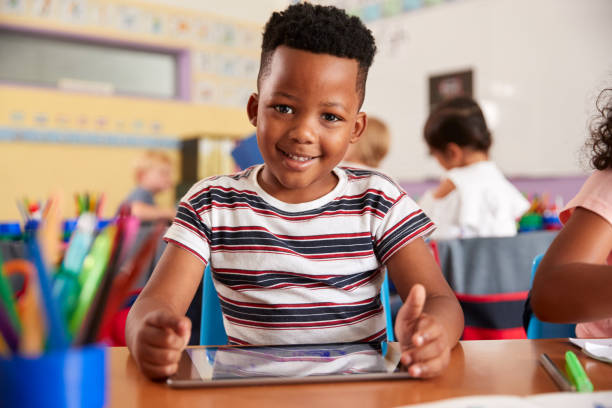 retrato de alumno masculino en el dibujo de la escuela primaria usando la tableta digital en el aula - africa african descent education child fotografías e imágenes de stock
