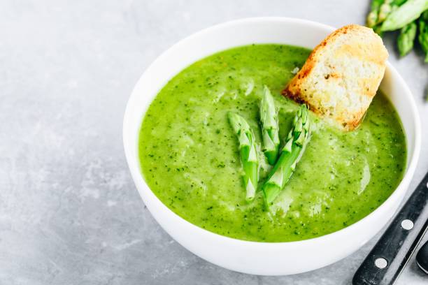 istock Asparagus cream soup with croutons on gray stone background. 1160928753
