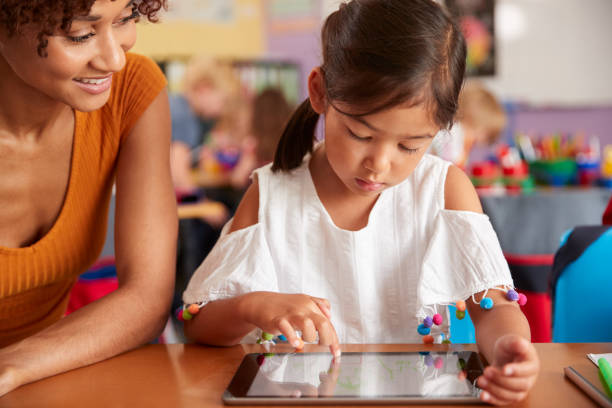 istock Elementary School Teacher And Female Pupil Drawing Using Digital Tablet In Classroom 1160928780