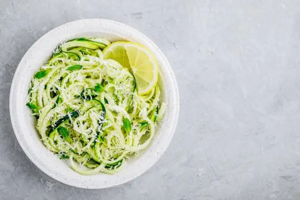 Photo of Green vegetarian pasta. Spiralized zucchini noodles with mint, lemon and parmesan cheese