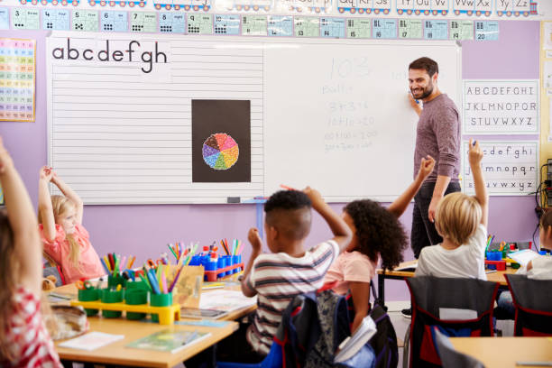 pupilas que levantam as mãos para responder à pergunta na lição elementar das matemáticas da escola - criança de escola fundamental - fotografias e filmes do acervo