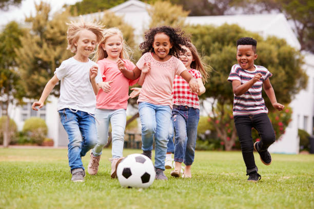 gruppo di bambini che giocano a calcio con gli amici a park - child playing running group of people foto e immagini stock