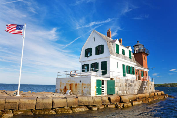 The Rockland Breakwater Lighthouse on a summer afternoon, with US flag flying. Rockland, Maine, USA