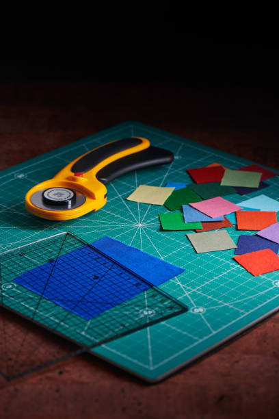 heap square pieces of colorful fabrics, rotary cutter and ruler on cutting mat - patch textile stack heap imagens e fotografias de stock
