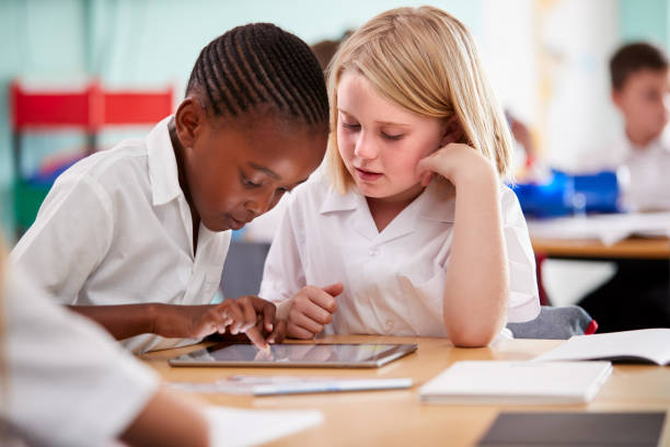 dwóch uczniów szkoły podstawowej w mundurku za pomocą cyfrowego tabletu przy biurku - elementary student school uniform uniform education zdjęcia i obrazy z banku zdjęć