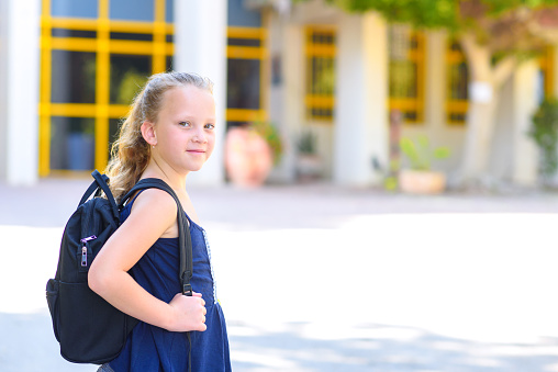 Portrair Happy smiling kid Back to school. Child little freckles girl with bag go to elementary school. Child of primary school. Pupil go study with backpack.