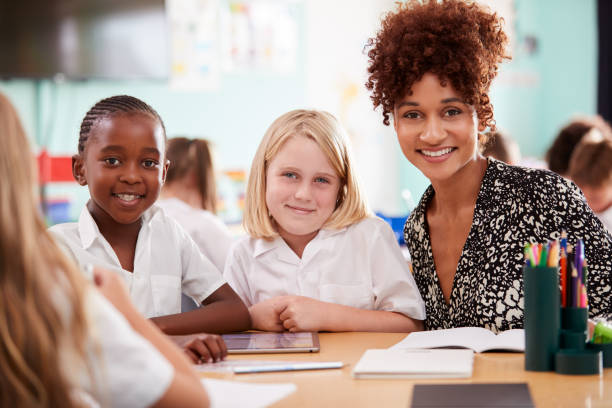 istock Portrait Of Female Teacher With Elementary School Pupils Wearing Uniform Using Digital Tablet 1160931079
