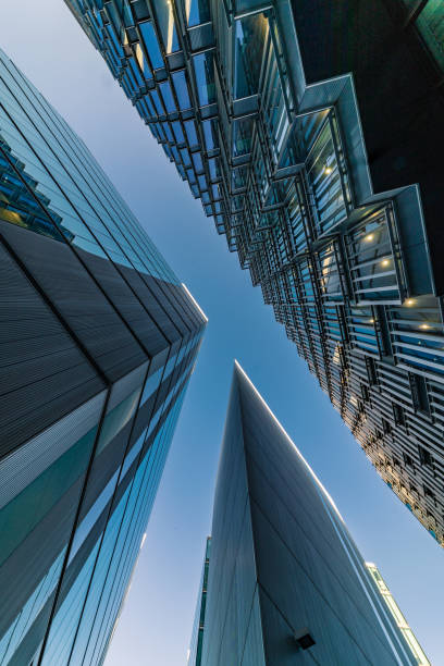 Abstract modern Business buildings in London's Financial District - stock image Highly detailed abstract wide angle view up towards the sky in the financial district of London City and its ultra modern contemporary buildings. Shot on Canon EOS R system, 14mm wide angle prime lens. Colour edit with high contrast ideal for background with copy space. image created 21st century blue architecture wide angle lens stock pictures, royalty-free photos & images