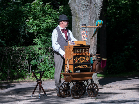 BERLIN, GERMANY - JUNE 8, 2019: A Barrel Organ Player With A Parrot In Berlin, Germany