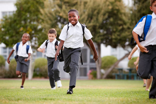 istock Excited Elementary School Pupils Wearing Uniform Running Across Field At Break Time 1160932611