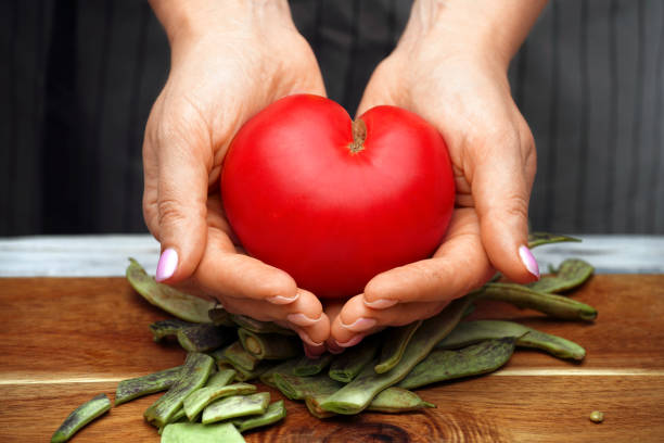 Tomato in the shape of a heart in female hands. Healthy food. stock photo