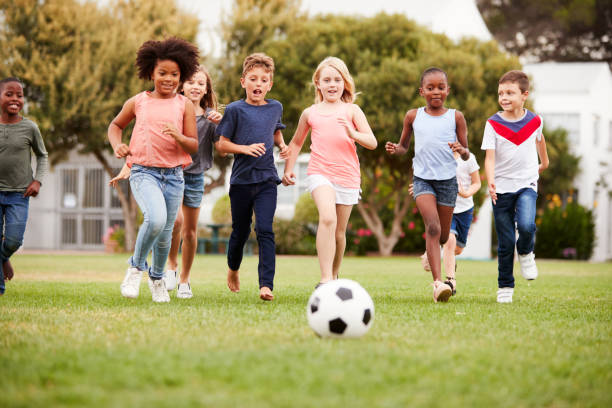 公園で友達とサッカーをする子供たちのグループ - 子供サッカー ストックフォトと画像
