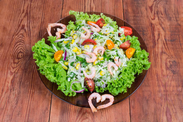 Shrimp salad with spinach leaves, radish slices and some carrot grated with olive oil, mustard seeds and balsamic vinegar. Selective focus. High key. Studio photography. Horizontal composition.