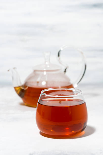 istock glass cup of tea and teapot on white background, vertical 1160939519